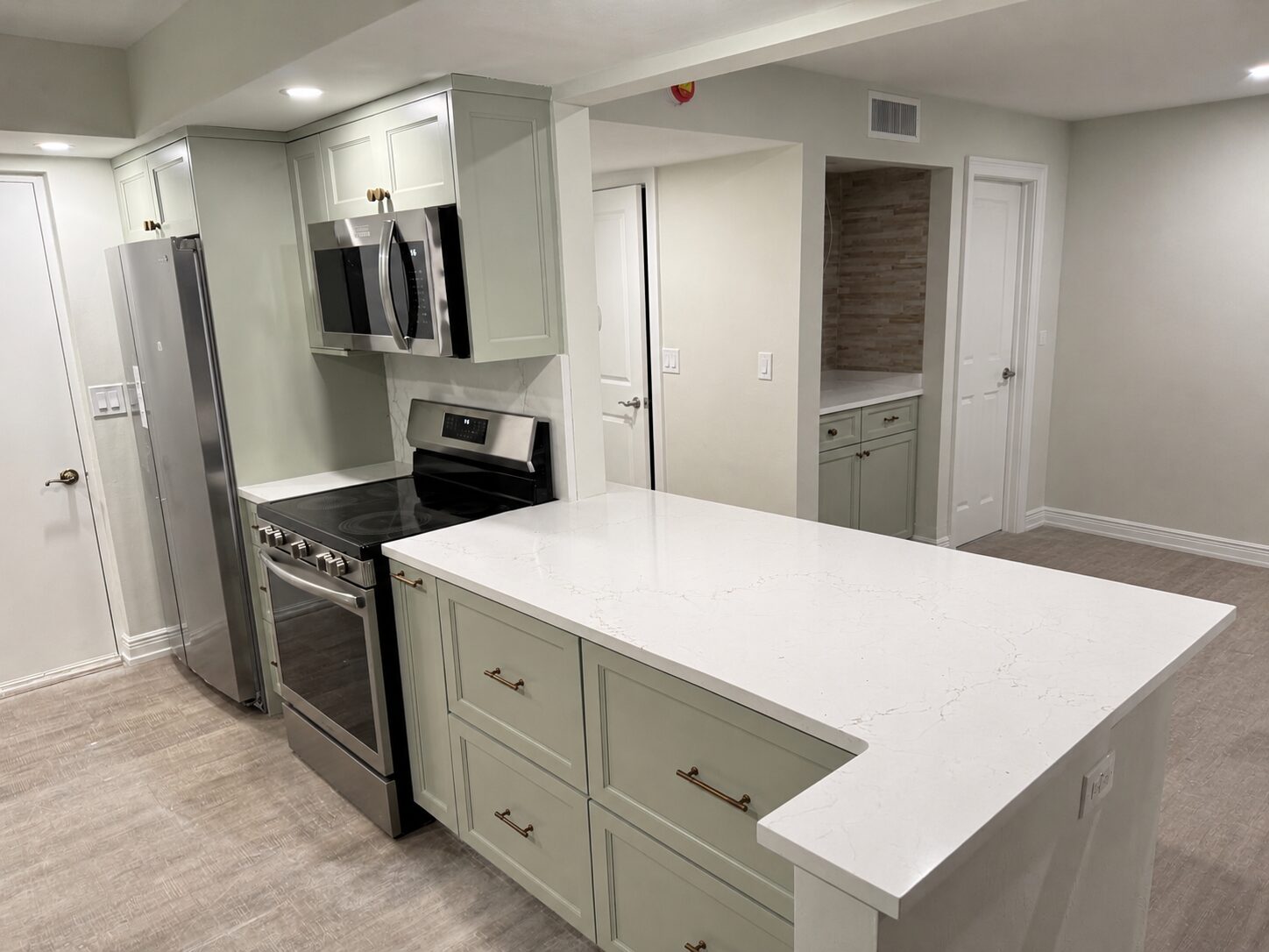 Sage-green condo kitchen renovation with quartz countertops in Naples